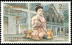 A girl in traditional Thai dress making a garland and sitting in front of the Cultural Arts Center at the Suan Dusit Teacher College
